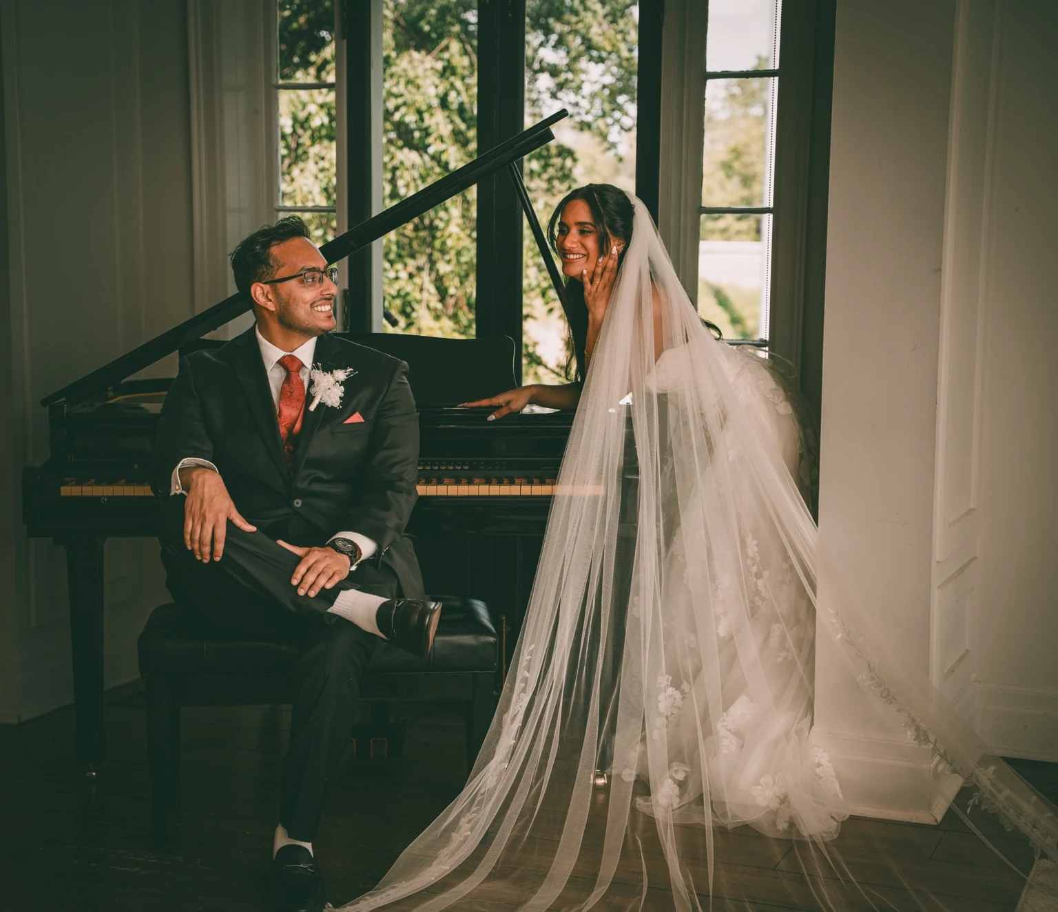 Bride and groom sharing a joyful portrait beside a piano