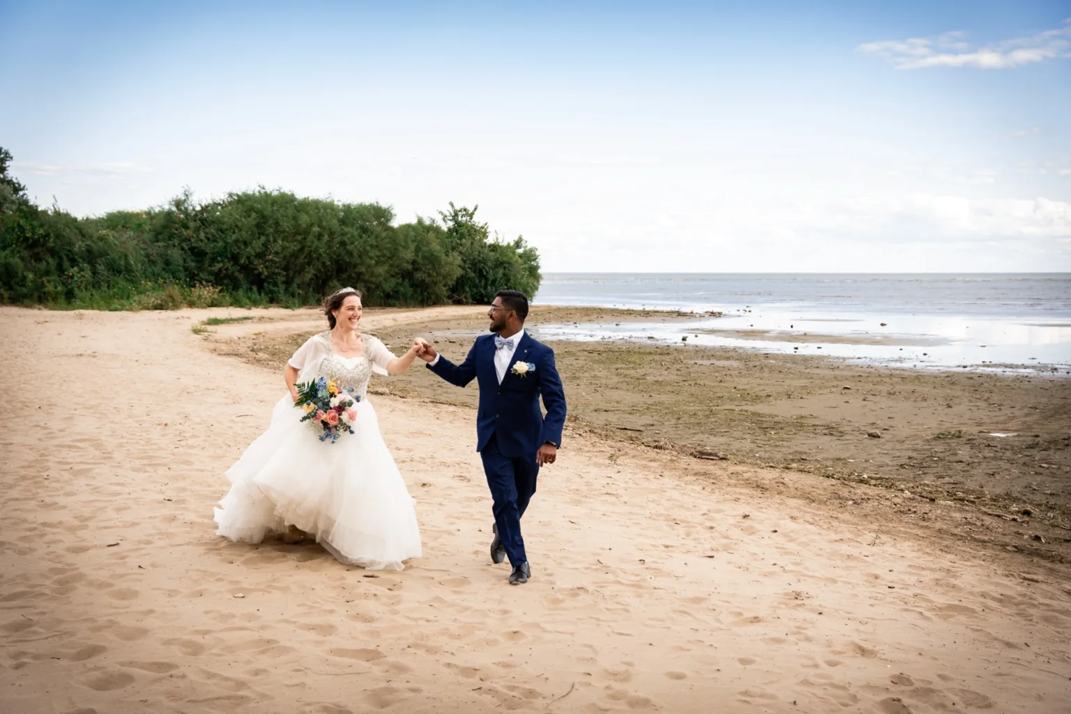Bride and groom walking on a beach during wedding portraits